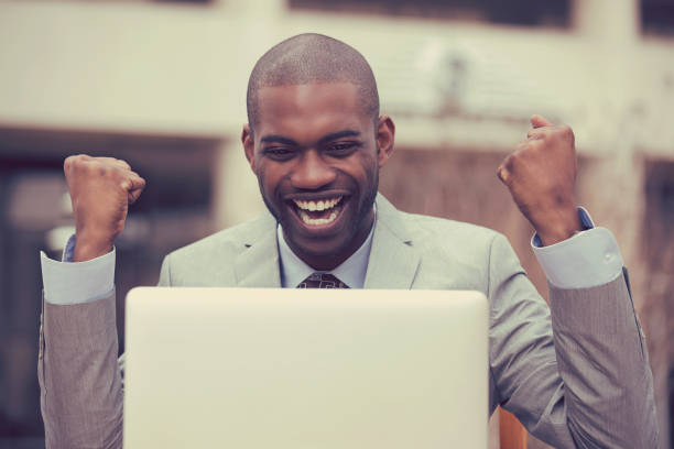 istock Happy successful young man with laptop computer celebrates success outside corporate office 670634802