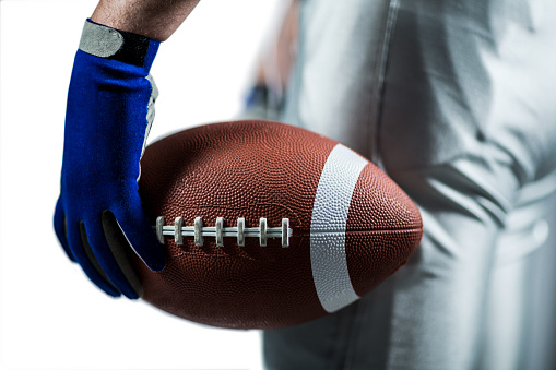 Cropped image of sportsman holding American football ball