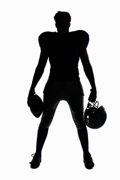 Silhouette American football player holding ball and helmet Silhouette American football player holding ball and helmet against white background safety american football player stock pictures, royalty-free photos & images