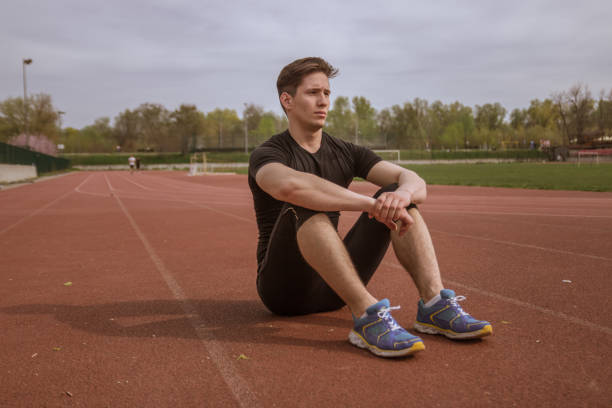 istock one young man, relaxing sitting on red running tracks, 670639284