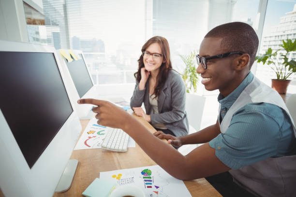 istock Businessman pointing at computer while sitting with coworker at desk 670642232
