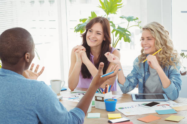 istock Happy business people discussing while working at desk 670645562