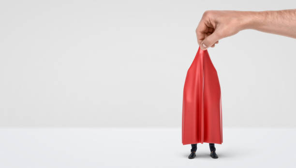 istock A giant hand taking off a red drapery from a hidden businessman on white background 670652222
