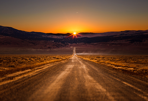 A single truck rides into the sunset on this dusty Nevada road