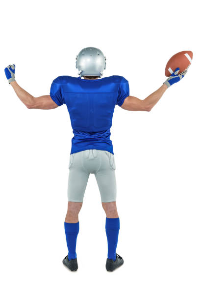 Full length rear view of American football player holding ball Full length rear view of American football player holding ball against white background american football player studio stock pictures, royalty-free photos & images