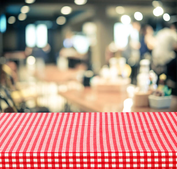 istock Empty table with red check table cloth over blurred cafe with bokeh background, food and product display montage 670664178