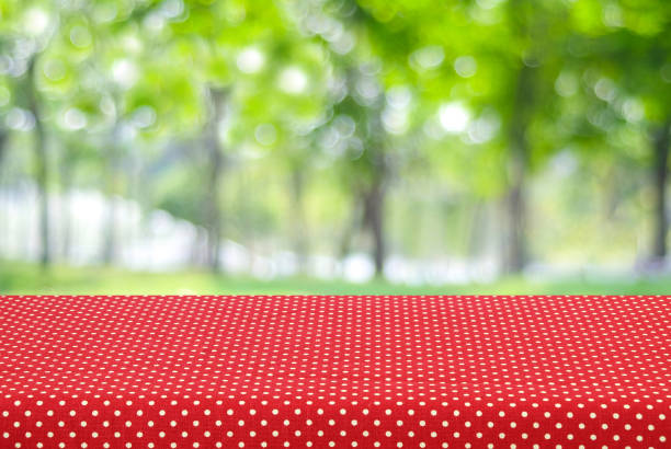 istock Empty table covered with red polka dot tablecloth over blur tree background, for food and product display montage 670664318