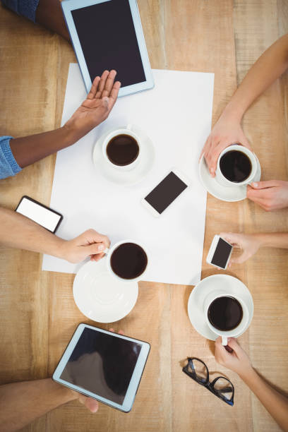 istock Overhead view of people using technology with person showing digital tablet 670665196