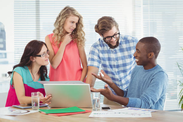 istock Man gesturing in front of coworkers in creative office 670669092