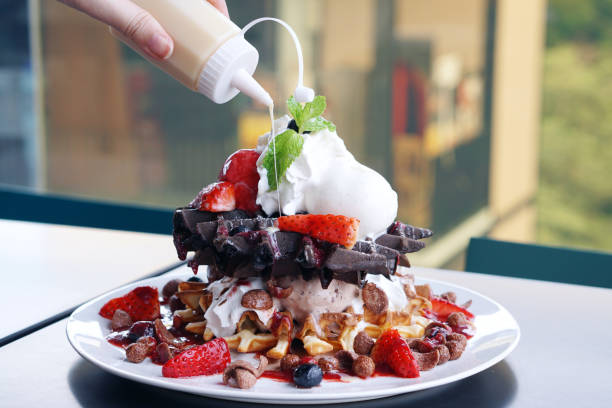 istock Stack of Waffles and ice cream topped with strawberries, blueberries, chocolate cereal, strawberries sauce and whipped cream 670672002