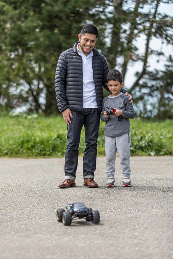 Stock photo of a happy father and son using a remote controlled car in the park