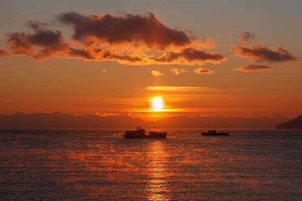 Two ships floating towards each other on background of red sunset