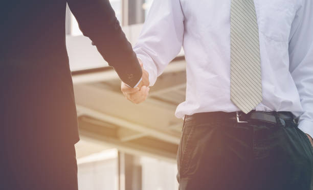 istock Two businessman hands shaking in modern town 670686280