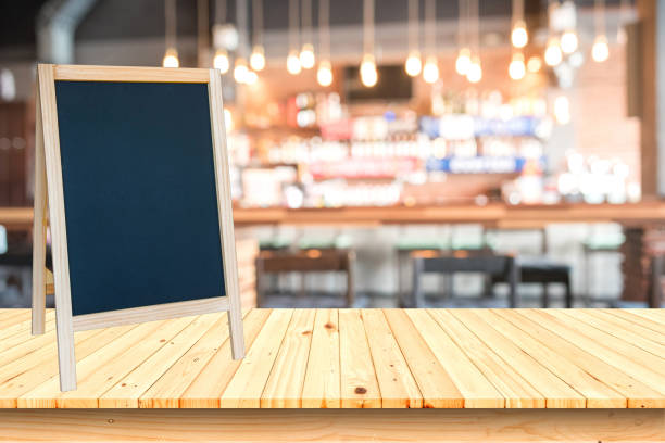 istock Blank blackboard sign and wooden table with blurred cafe background. 670686320
