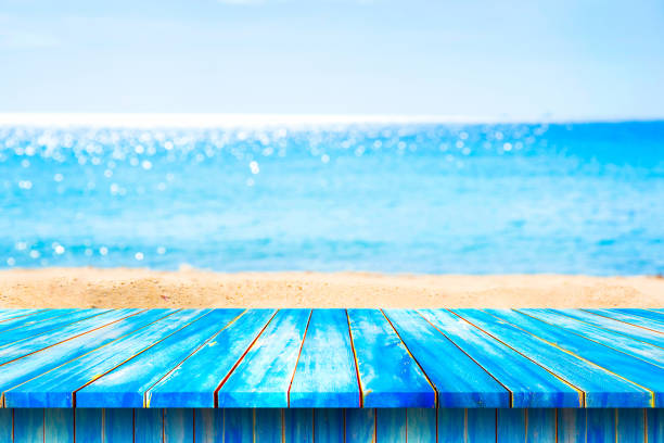 istock Blue wooden table top on blurred beach background for product display. 670697176