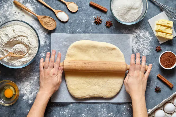 Photo of Dough bread, pizza or pie recipe traditional preparation. Female chef cook hands rolling dough with pin