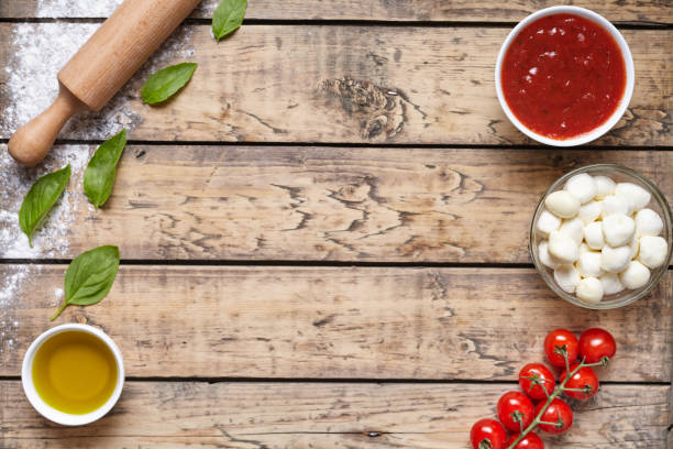 istock Rustic traditional Italian food background with empty copy design space on aged wooden texture table. Basil, olive oil, tomato sauce, rolling pin, tomatoes. 670702146