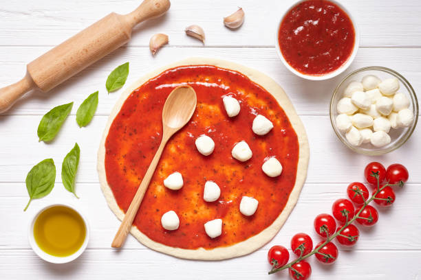istock Pizza preparation. Ingredients on the kitchen table: rolled dough with tomatoes sauce, basil, olive oil, mozzarella cheese 670702386