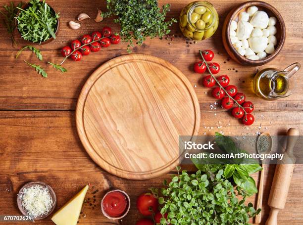 Cutting Wooden Board With Traditional Pizza Preparation Ingridients Mozzarella Tomatoes Sauce Basil Olive Oil Cheese Spices Stock Photo - Download Image Now