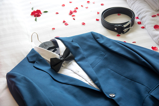 Suit and belt on the bed for a wedding ceremony.