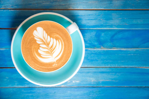 istock Hot latte coffee in cup on blue wooden table. 670709338