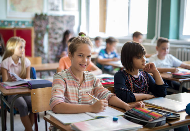 istock Smiling schoolboy writing in the classroom and looking at camera. 670713010