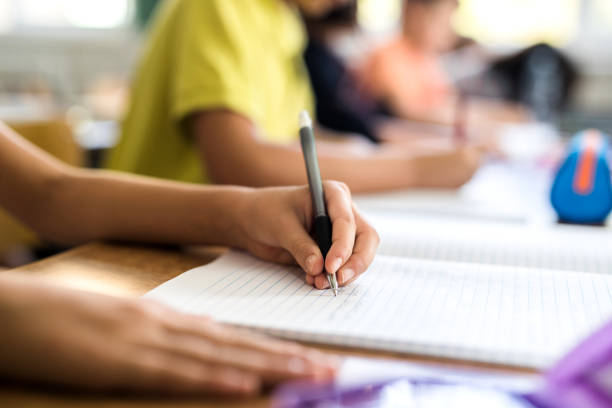 Close up of left handed school child writing in notebook.