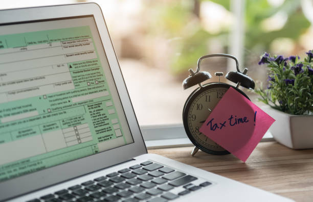 tax time online tax time post-it on alarm clock and Individual income tax return form online. tax season photos stock pictures, royalty-free photos & images