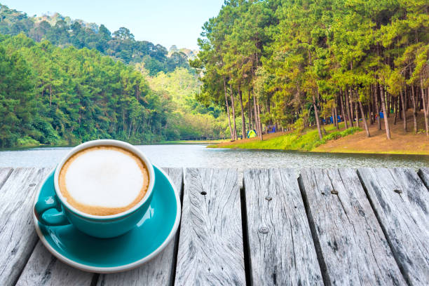 istock Cappuccino on a wooden table and Green forest landscape. 670719502