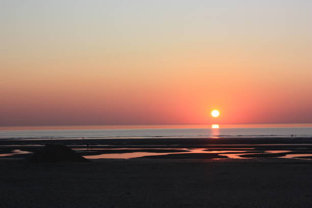 Sunset on the beach at low tide Sunset on the beach at low tide - Reflection on the water tables reflet stock pictures, royalty-free photos & images