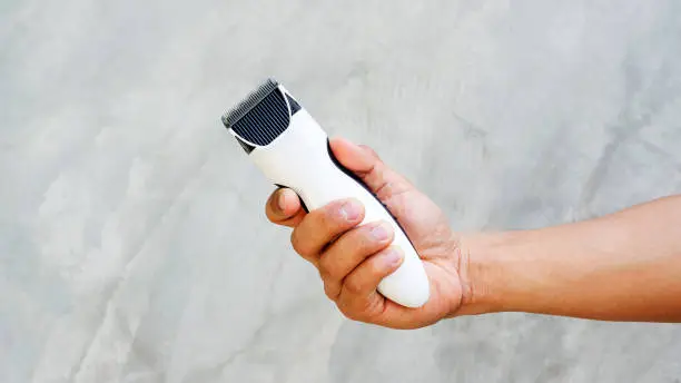 Man holding wireless hair clipper in his hand.