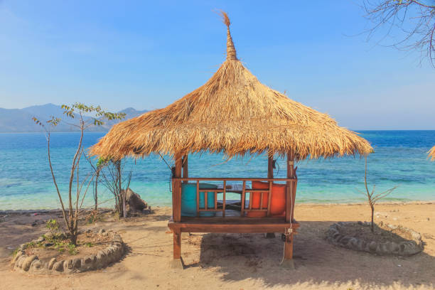 Traditional Bali gazebo,with two colorful pillow on the seater. The beach hut is on the seaside, with overlook of the blue ocean and sky.