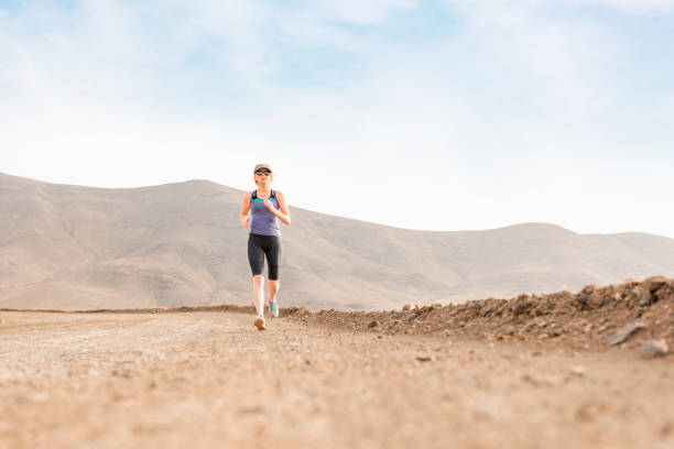 istock Athletic Lady Jogging on Dirt Road with Mountains in Background 670731328