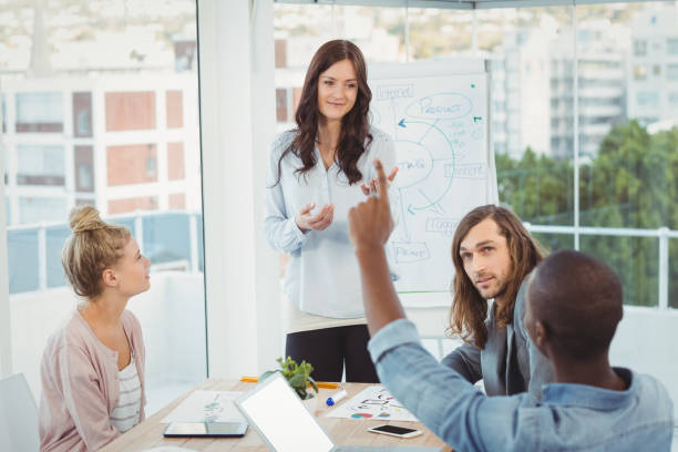 istock Rear view of man with hand raised while discussing with coworkers 670737062