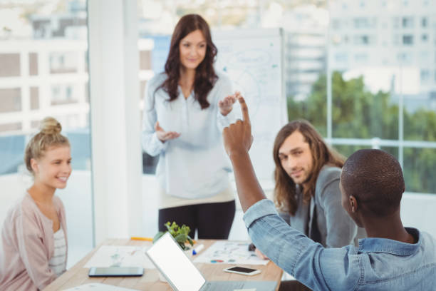 istock Man with hand raised while discussing with coworkers 670737158