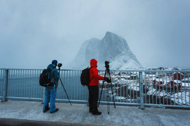 Two photographers take a pictures of Hamnoy village during the snowstorm