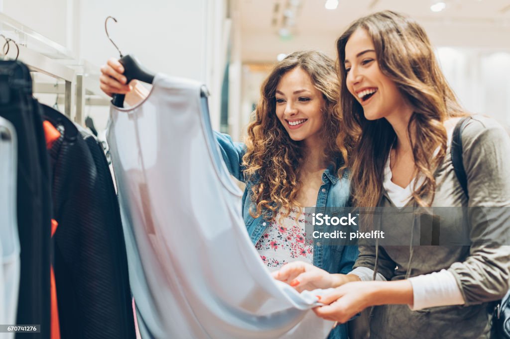 Two cheerful girls shopping for clothes Two young women in the fashion store Shopping Stock Photo