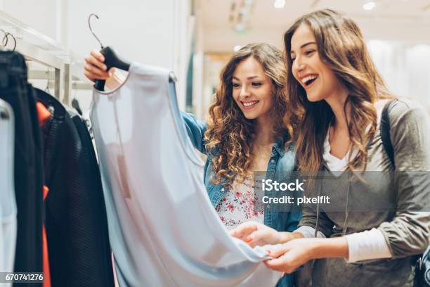 Two Cheerful Girls Shopping For Clothes Stock Photo - Download Image Now - Shopping, Retail, Clothing
