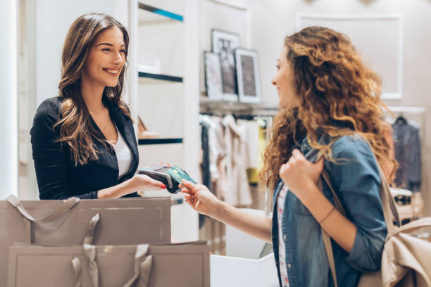Credit card payment in the fashion store Young woman giving her credit card for a contactless payment in the fashion store clothing store credit card stock pictures, royalty-free photos & images