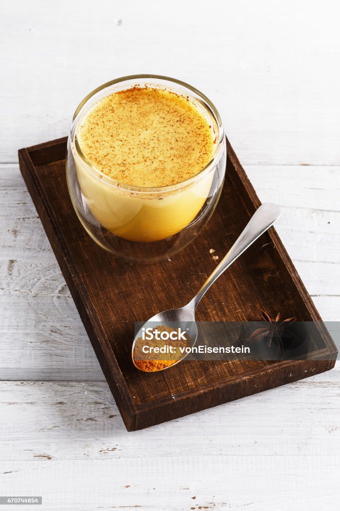 Close up image of golden latte over white wooden table Close up image of golden latte in a wooden box over white wooden table Turmeric Stock Photo