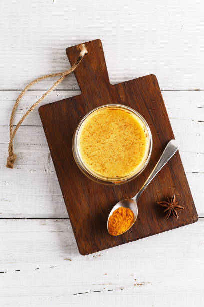 Flat lay view of golden latte over white wooden table stock photo