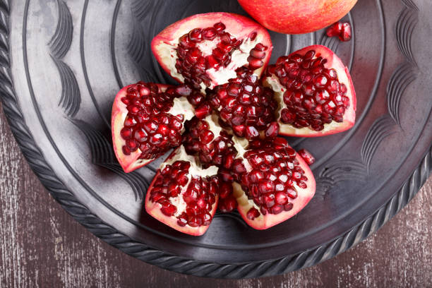 istock Ripe pomegranate fruit and seeds on dark dish. Top view. 670747544