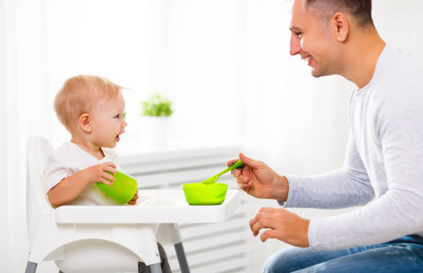 istock father feeds baby from spoon 670752520