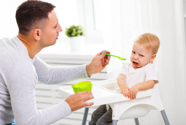 vater füttert den weinenden babysohn - 5944 stock-fotos und bilder