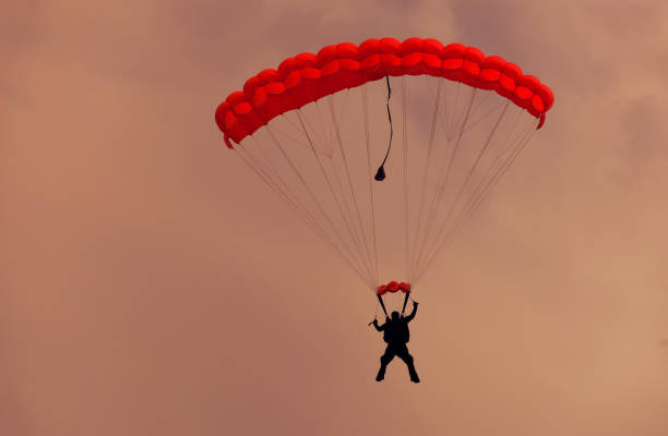 istock Male parachutist makes the jump on a red parachute. 670771432