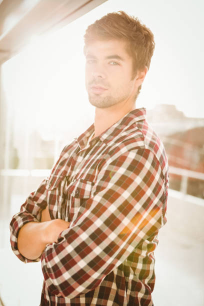 istock Confident hipster with arms crossed standing by window 670776082