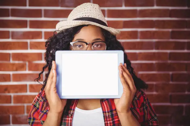 Photo of Hipster looking at camera showing tablet
