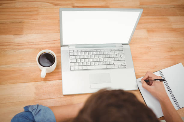 istock Hipster writing on spiral notebook by laptop at desk in office 670782688