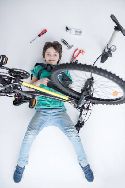 istock top view of smiling boy while lying under bicycle on white 670782944
