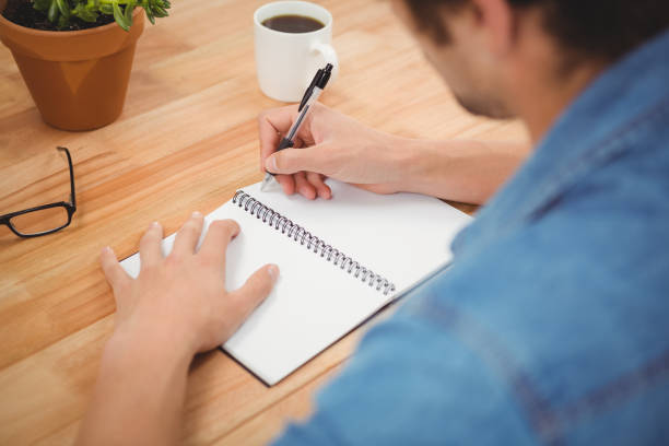 istock Hipster writing on spiral book at desk 670785498